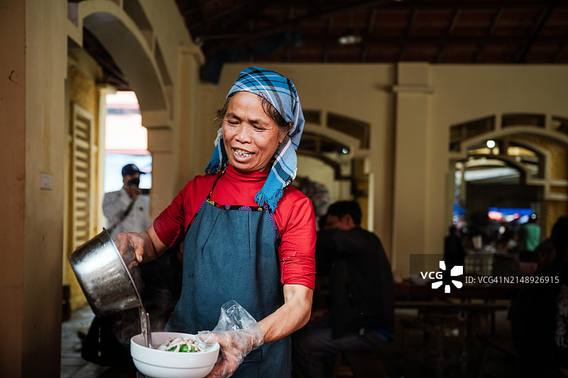 在越南坝荷市场街头餐厅做饭的土著老年妇女图片素材