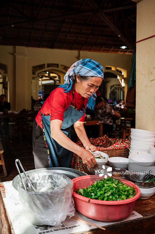 在越南坝荷市场街头餐厅做饭的土著老年妇女图片素材