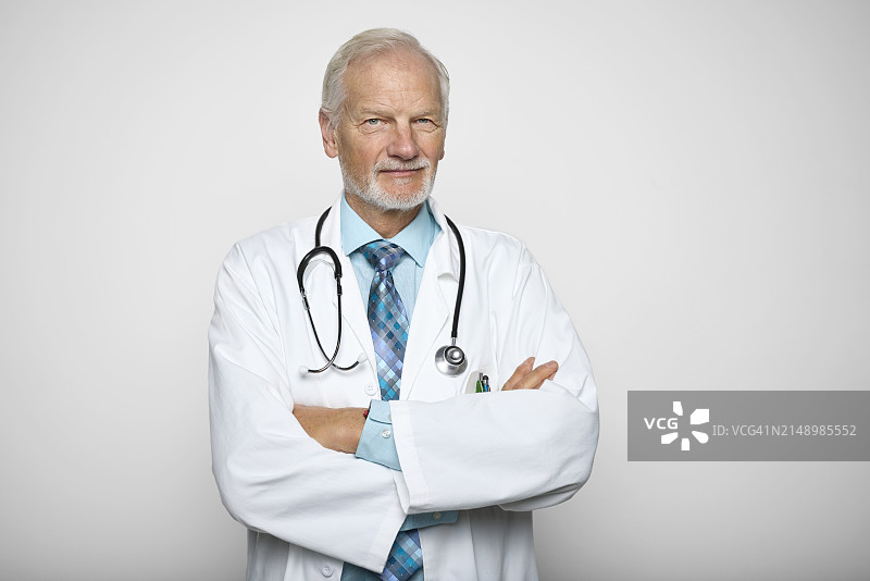 自信的年长医生，双臂交叉，背景为白色图片素材