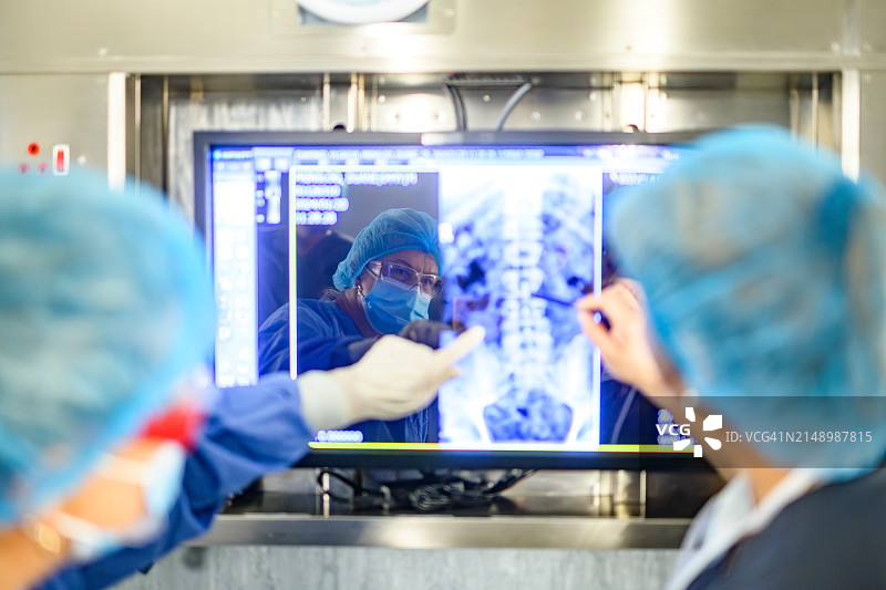 女外科医生在手术中看着X光片的正面反射，讨论手术过程的背面图图片素材