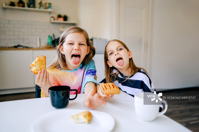 两个年轻女孩在家中厨房吃零食图片素材