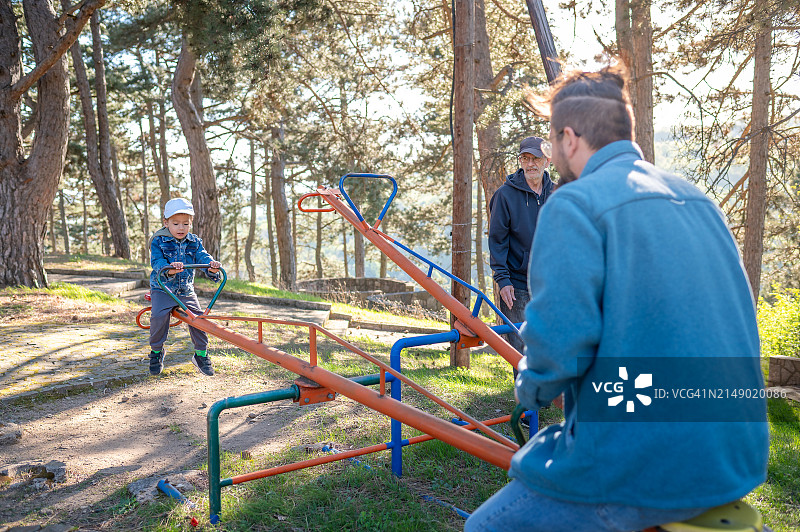 儿童和成年人在公园玩跷跷板图片素材