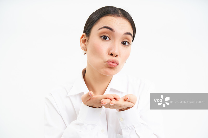 可爱的办公室女士在手掌上送飞吻，嘟着嘴对着镜头温柔地看图片素材