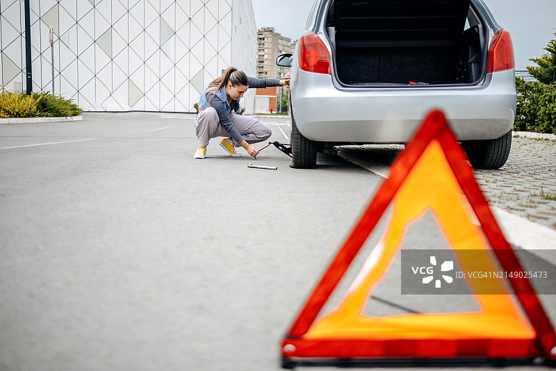 女人用千斤顶更换汽车的瘪胎图片素材