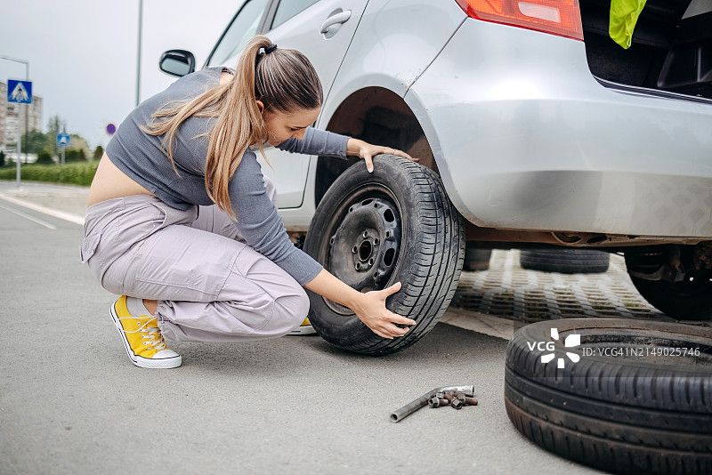 女人更换汽车的瘪胎图片素材