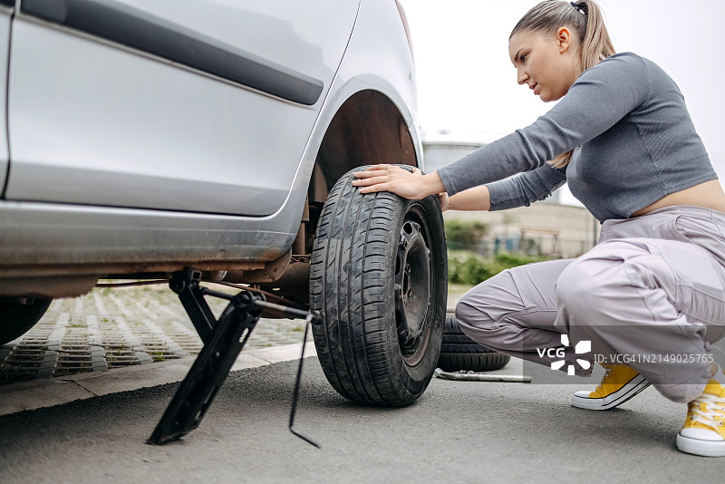 女人更换汽车的瘪胎图片素材