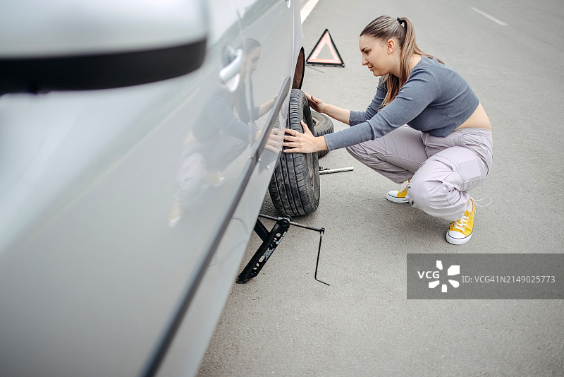 女人更换汽车的瘪胎图片素材