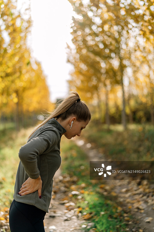 秋季，在人行道上慢跑的年轻女子侧视图图片素材