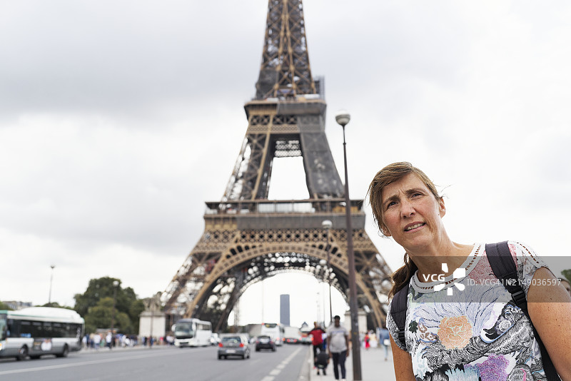 在巴黎铁塔背景下，休闲装游客女性的正面微笑肖像图片素材