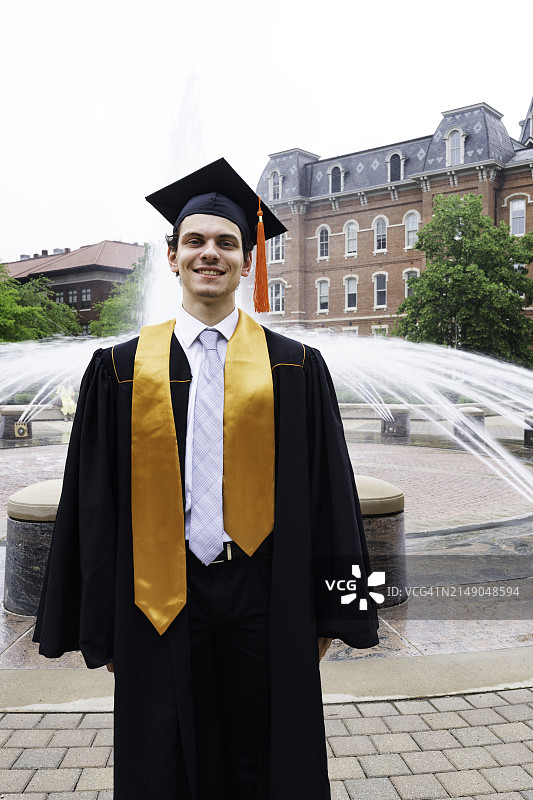 戴着帽子和毕业礼服的快乐男大学毕业生图片素材