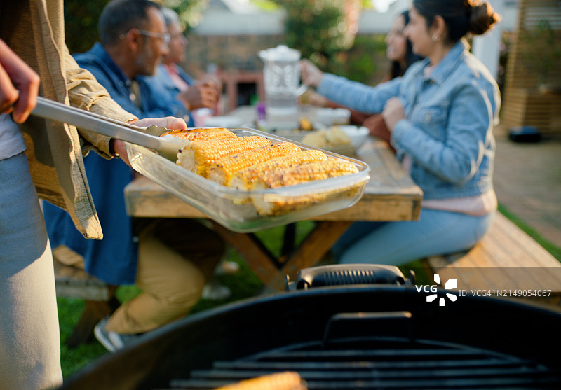 烧烤派对：花园里手拿玉米的人们图片素材