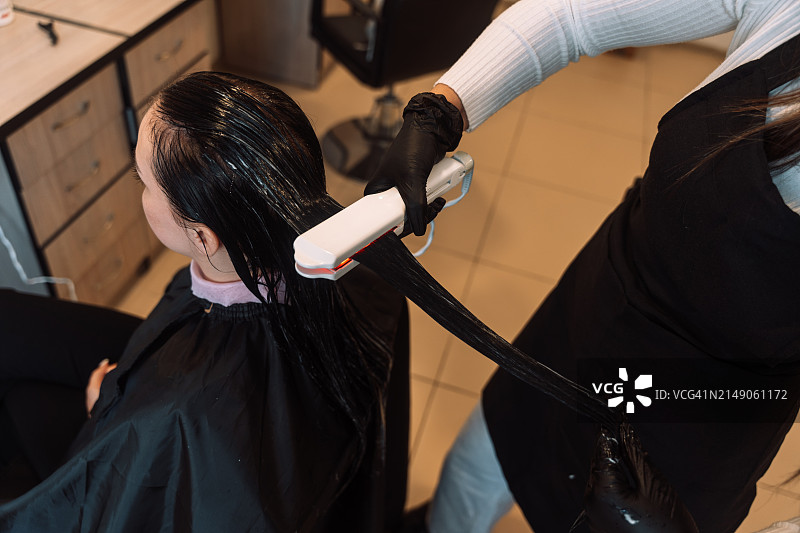 理发师使用红外线冷烫进行头发护理和肉毒杆菌程序图片素材