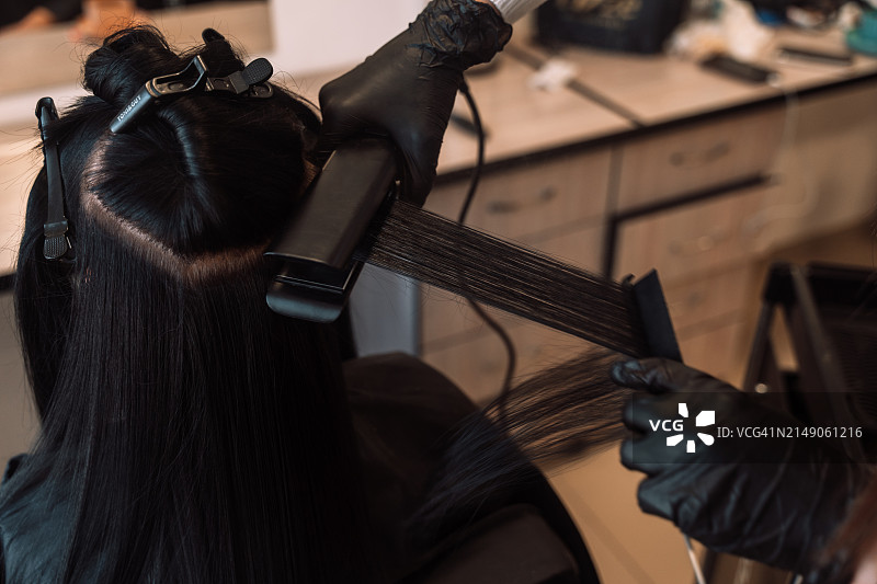 发型师使用特氟龙涂层拉直器蒸发头发中的角蛋白和肉毒杆菌图片素材
