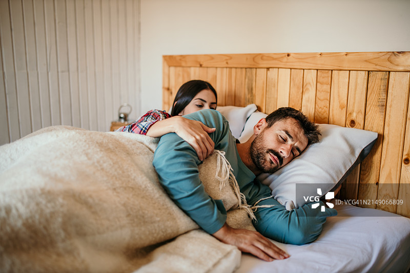 已婚夫妇在舒适的室内床上相拥而眠图片素材