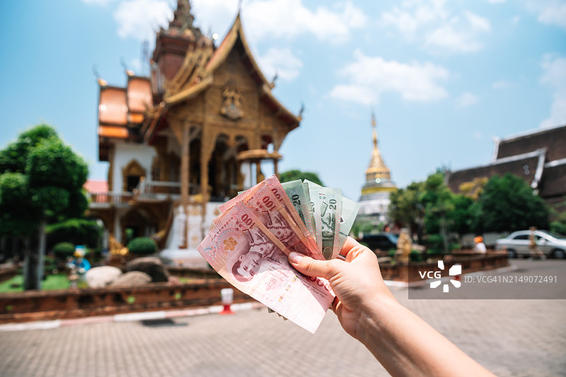 手持泰国纸币，清迈佛教寺庙背景图片素材
