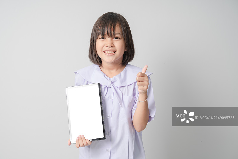 穿校服的女孩展示平板电脑并竖起大拇指图片素材