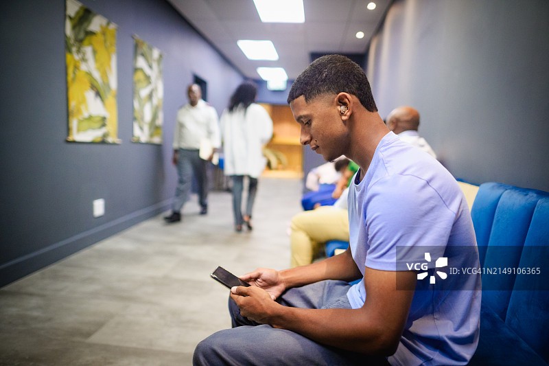 在医疗候诊室接待处等待时使用助听器的男人图片素材