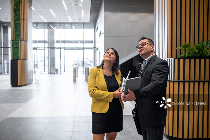 穿着商务休闲的快乐商务人士在办公楼里交谈图片素材