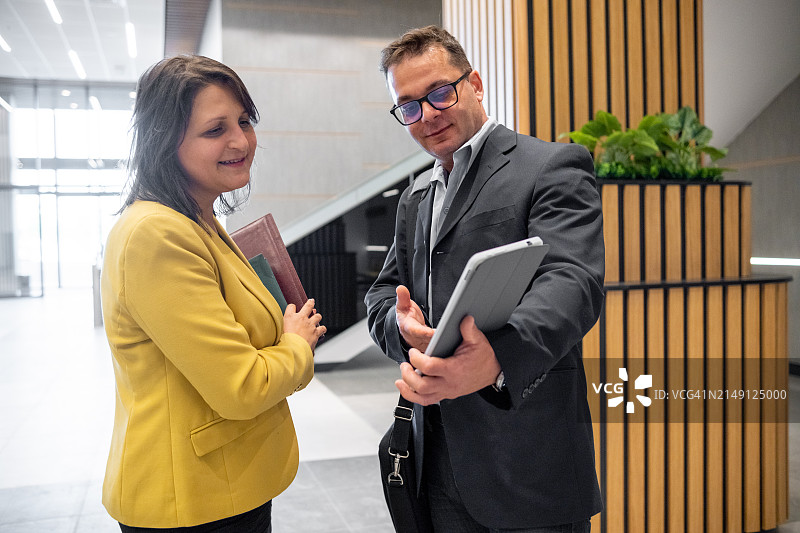 一位快乐的商人和一位穿着商务休闲装的商人在商业大楼里交谈图片素材