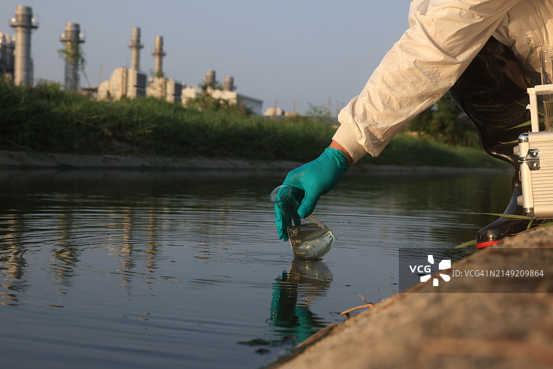 科学家戴丁腈手套收集废水样本进行水质分析特写，工业环境概念图片素材