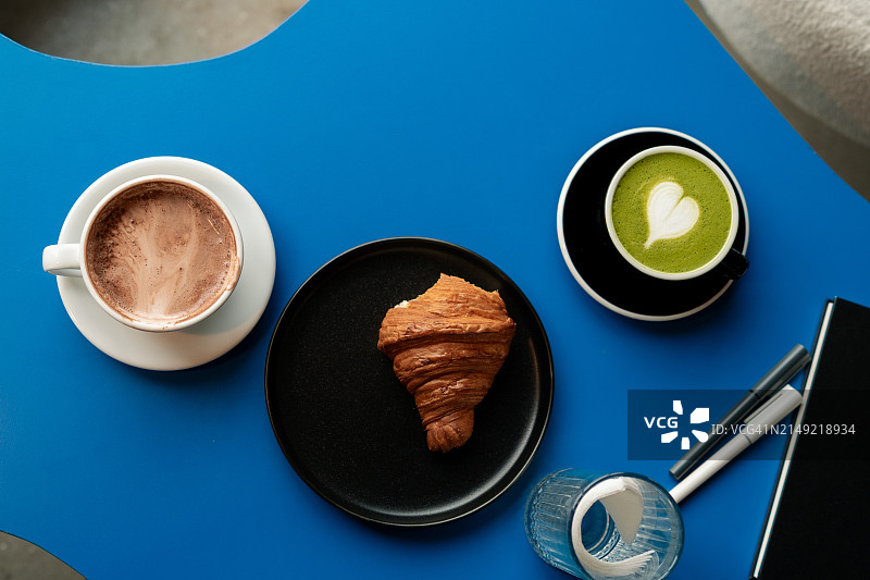 桌子上抹茶、咖啡和羊角面包的俯视图图片素材