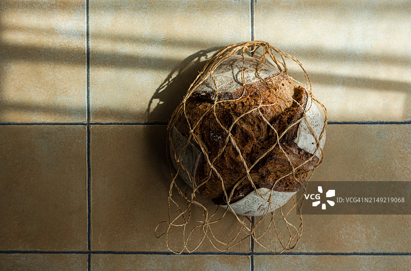 瓷砖桌上装在网袋里的酸面包黑麦面包的俯视图图片素材