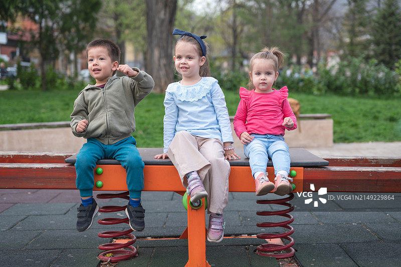 三个孩子在春天跷跷板上欢笑图片素材
