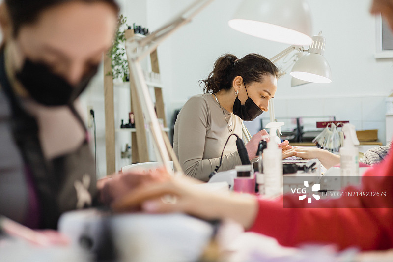 专业美甲师自信地为顾客涂指甲油图片素材