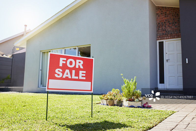 仰视角度拍摄的郊区住宅前的“出售”标志图片素材