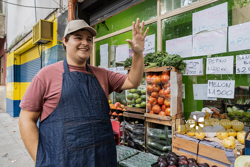 男销售在食品店入口迎接顾客图片素材