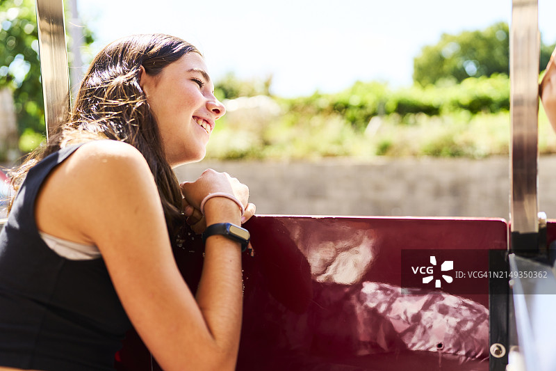 阳光明媚的日子里，靠在车窗旁的黑法兰绒少女图片素材