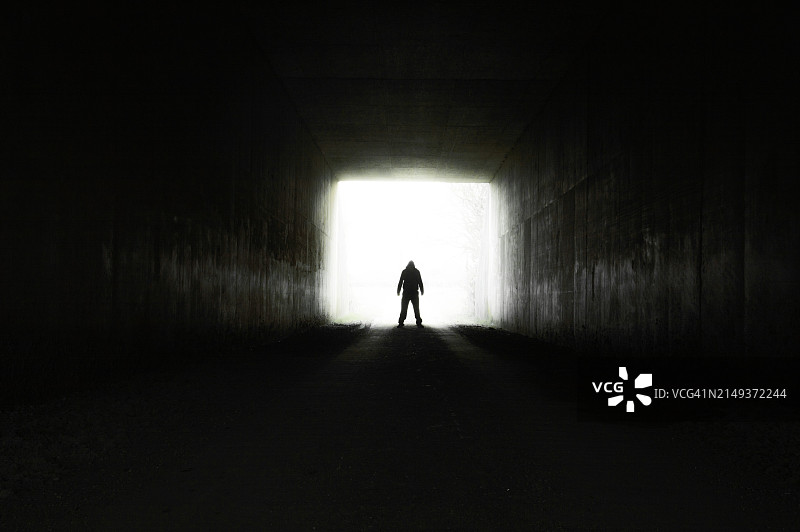 站在黑暗隧道入口处的恐怖兜帽人图片素材
