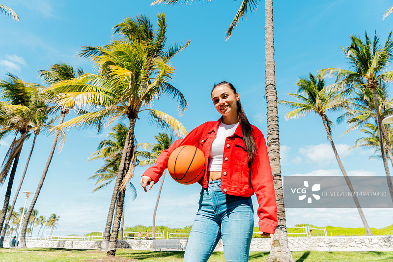 年轻女人在公园拿着篮球的肖像图片素材