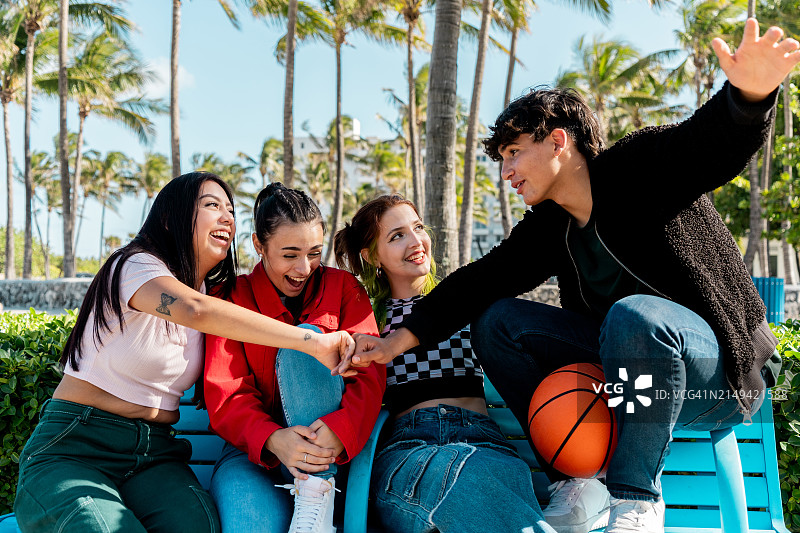 朋友们坐在公园长椅上聊天图片素材