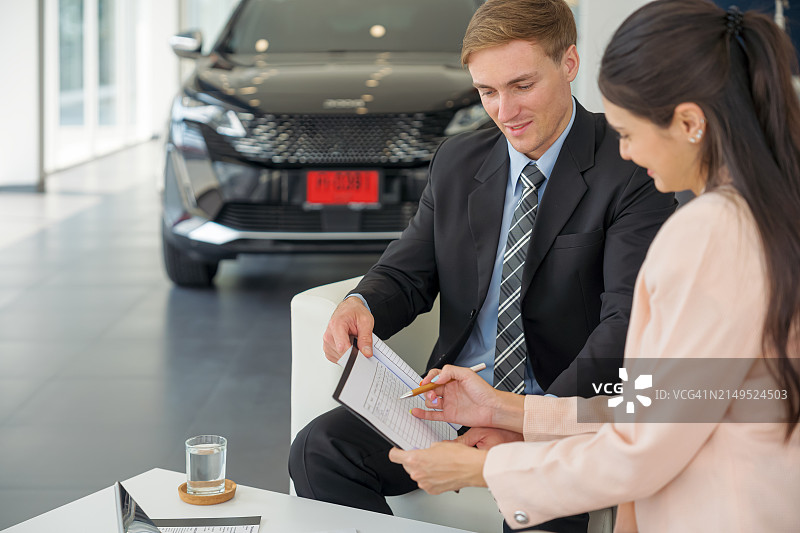 汽车经销商和女顾客在汽车展厅处理文件图片素材