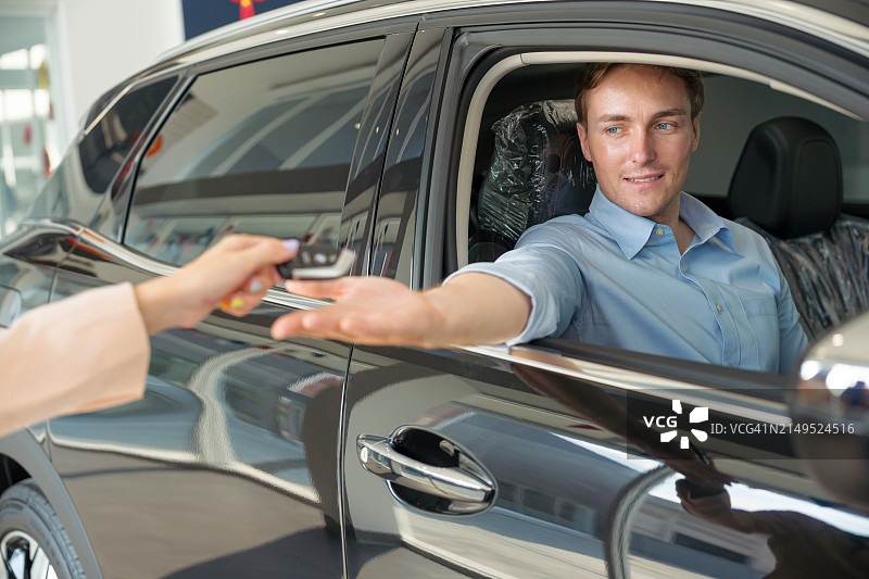 快乐的男人在展厅里收到他的新车钥匙图片素材