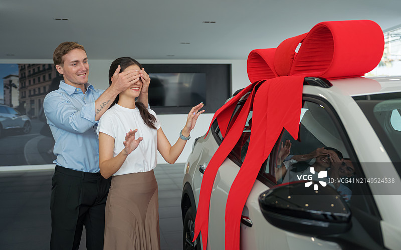 中年男人在汽车经销店用新车给妻子惊喜图片素材