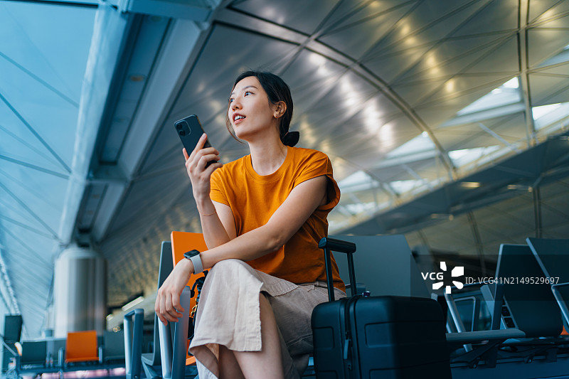 年轻亚洲女人机场商务旅行使用手机图片素材