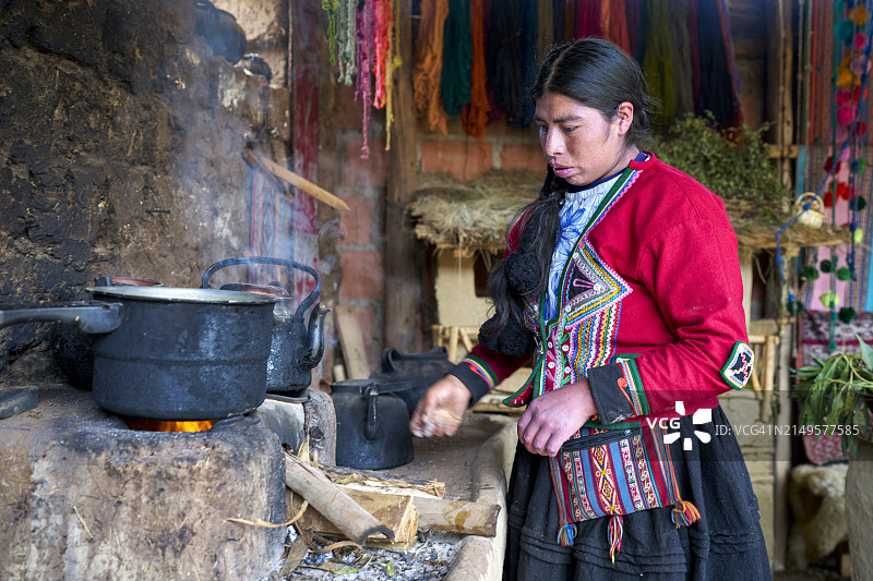 来自秘鲁钦切罗镇的本土女织工在火上为罐子加热，提取面料着色图片素材