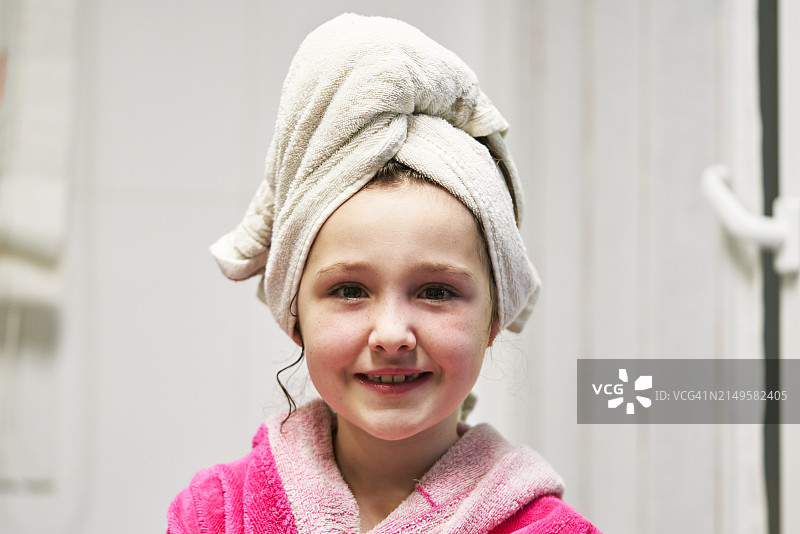 一位头发上裹着浴巾的微笑女孩的面部肖像，正面视角图片素材