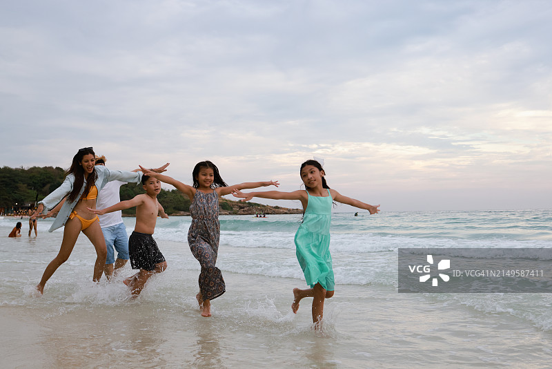 幸福的亚洲家庭在热带海滩上迎接日出，享受夏季假期和旅行图片素材