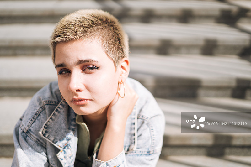 城市楼梯上坐着的悲伤短发少女肖像图片素材