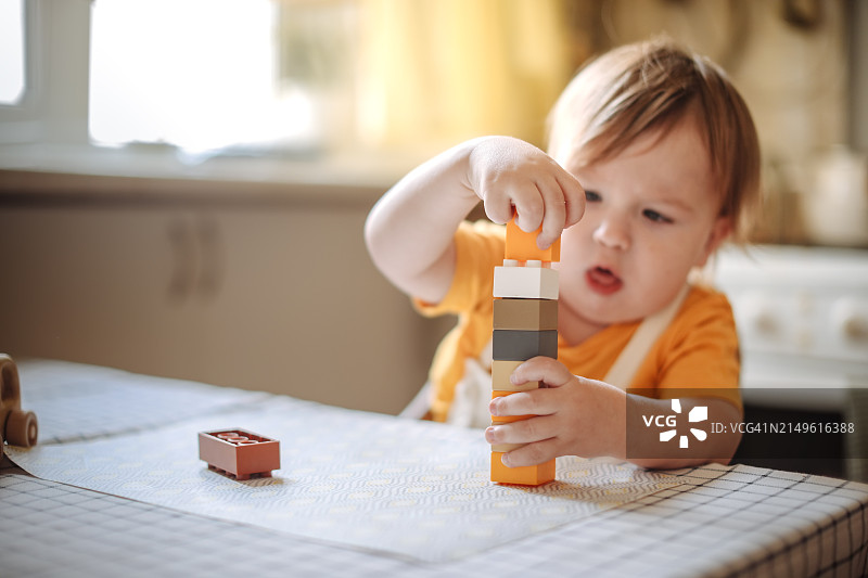 童年孤独：忧郁的幼儿独自玩塑料积木，表达悲伤情绪图片素材