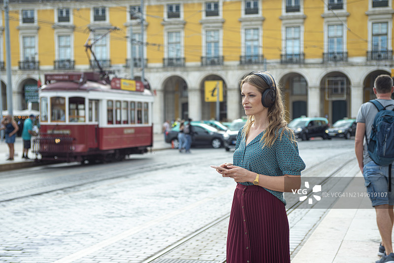 女人在里斯本商业广场用手机听音乐图片素材
