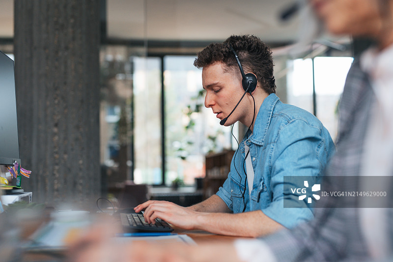 年轻的公司职员戴着耳机打电话图片素材