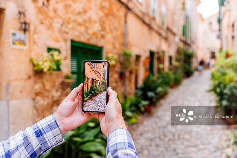 游客在西班牙马略卡岛瓦尔德莫萨村用智能手机拍摄小巷图片素材