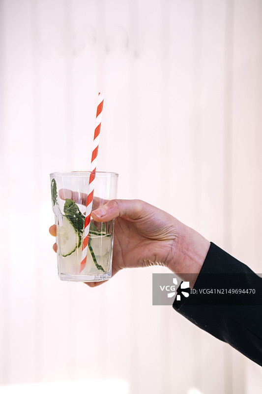 女人在墙前手持一杯黄瓜汁图片素材