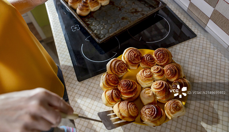 年长的女人在家中厨房把甜面团包子放在盘子里图片素材