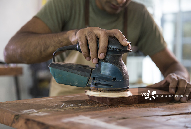 木匠在车间使用砂光机抛光木块图片素材