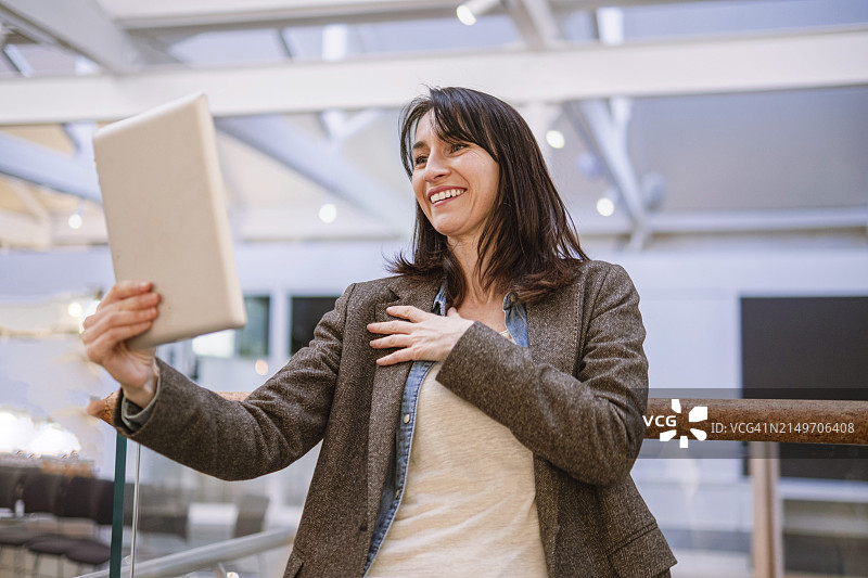 快乐的女人在讲堂里用平板电脑进行视频通话图片素材